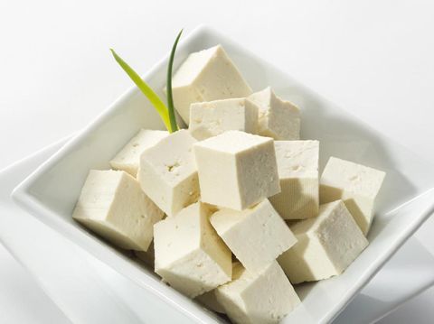Tofu cubes in a white bowl garnished with spring onion.