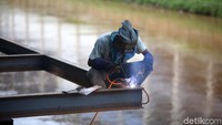 Pekerja mengelas besi untuk penopang deck view yang berada di atas sungai.