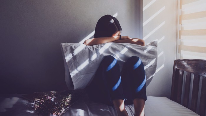 Ilustrasi wanita sedih Asian women are sitting hugging their knees in bed. Feeling sad, disappointed in love In the dark bedroom and sunlight from the window through the blinds.Vintage tone.