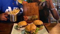 Bersama sang tunangan, Bobby pasang pose seru dengan piagam Muscle Beach Bali 2019, sambil menyantap kentang goreng dan burger sebagai momen perayaan mereka. Foto: Instagram @bobbyida