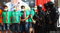 Para tersangka dihadirkan dengan penjagaan polisi bersenjata lengkap.