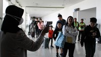 Seorang petugas mengecek suhu tubuh penumpang yang baru turun dari pesawat pada Rabu (2212020). Antara Foto/Umarul Faruq.