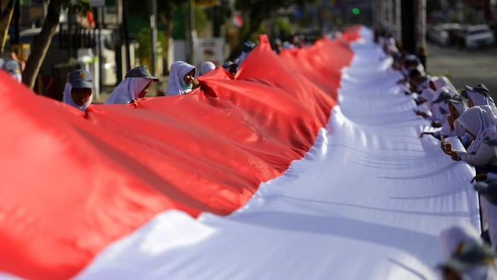 Sejumlah pelajar membentangkan kain merah putih di Kota Gorontalo, Gorontalo, Kamis (23/1/2020). Pembentangan kain merah putih dalam rangka Hari Patriotik Provinsi Gorontalo ke-78 tersebut meraih rekor MURI dengan panjang kain 2.300 meter dan lebar 3 meter. ANTARA FOTO/Adiwinata Solihin/pras.