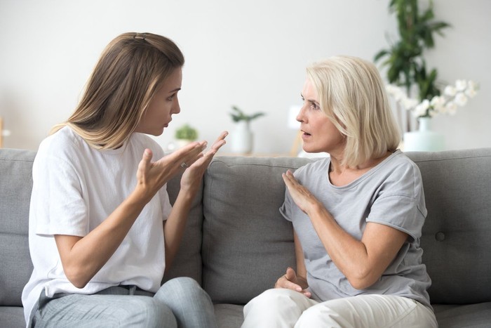 ibu dan anak Angry young woman has disagreement with annoyed old mother in law, grown daughter arguing fighting quarreling with senior elderly mom, different age generations bad relations family conflict concept