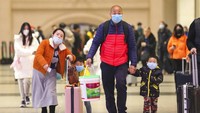 Satu keluarga mengenakan masker pelindung pernapasan saat akan mudik ke kampung halaman menjelang Tahun Baru Imlek. Chinatopix via AP.