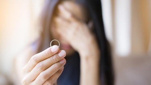 The woman holds the wedding ring and weeps.
