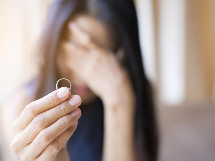 The woman holds the wedding ring and weeps.