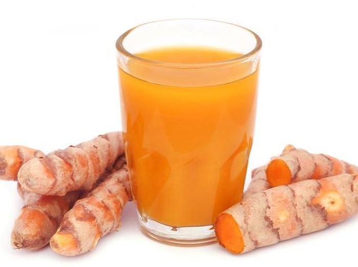 minuman dari tanaman herbal Turmeric golden milk latte with spices and honey. Detox, immune boosting, anti inflammatory healthy cozy drink. Female hands holding a cup