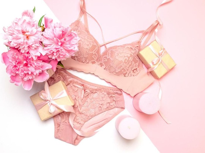 Female elegant pink lace bra and panties, flowers pink candles, a bouquet of beautiful peonies, gifts with pink ribbons, top view