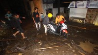 Warga membantu seorang pengendara motor melintas di jalan yang penuh lumpur saat terjadi banjir bandang di Petungsewu, Dau, Malang, Jawa Timur, Jumat (24/1/2020). ANTARA FOTO/HY Prabowo.