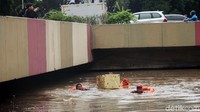 Tingginya air membuat petugas PPSU harus berenang untuk memunguti sampah.