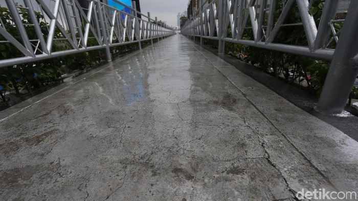 JPO di kawasan Sudirman tampak lengang akibat derasnya hujan yang mengguyur Jakarta. Tanpa atap, fasilitas tersebut seakan lumpuh.
