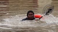 Petugas PPSU tetap sigap membersihkan sampah meski banjir yang merendam cukup tinggi.