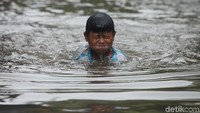 Banjir dimanfaatkan oleh anak-anak untuk berenang.