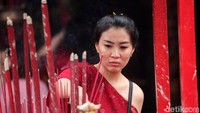 Seorang warga menyalakan hio atau dupa sebelum bersembahyang di dalam wihara.