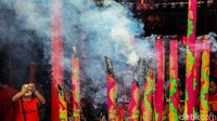 Warga berdoa sambil menyalakan hio atau dupa. Lilin berbagai ukuran juga dinyalakan di dalam wihara.