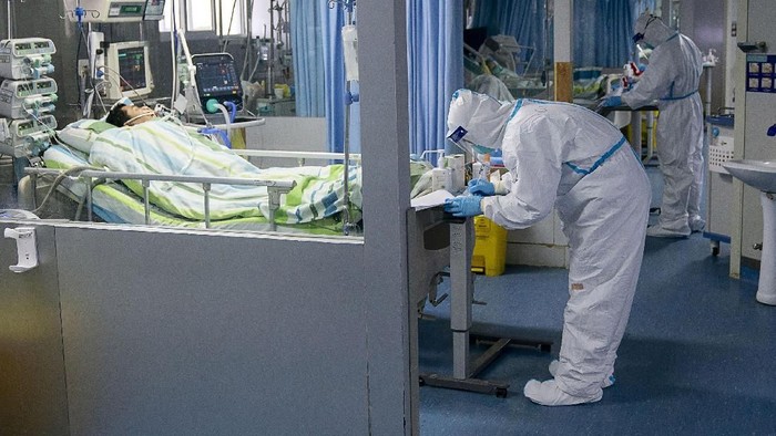 Melihat Penanganan Pasien Virus Corona di China In this Thursday, Jan. 23, 2020, photo, a staff member wearing a hazardous materials suit hauls a bin at a hospital that reported a coronavirus death in Yichang in central Chinas Hubei Province. China is swiftly building a 1,000-bed hospital dedicated to patients infected with a new virus that has killed 26 people, sickened hundreds and prompted unprecedented lockdowns of cities during the countrys most important holiday. (Chinatopix via AP)