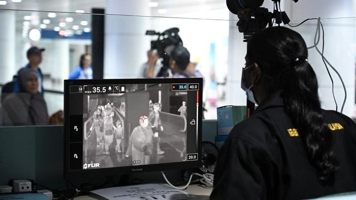 A Malaysian health officer screens arriving passengers with a thermal scanner at Kuala Lumpur International Airport in Sepang on January 21, 2020 as authorities increased measure against coronavirus. - China has confirmed human-to-human transmission in the outbreak of a new SARS-like virus as the number of cases soared and authorities January 21 said a fourth person had died, as the World Health Organization said it would consider declaring an international public health emergency over the outbreak. (Photo by MOHD RASFAN / AFP)