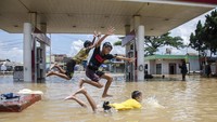 Sejumlah anak bermain di genangan banjir di Jalan Raya Baleendah, Kabupaten Bandung, Jawa Barat, Minggu (26/1/2020).