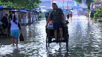 Dengan naik becak, warga menerobos banjir.