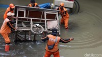 Sejumlah petugas masih berupaya membersihkan sampah dan menyedot air hingga tuntas.
