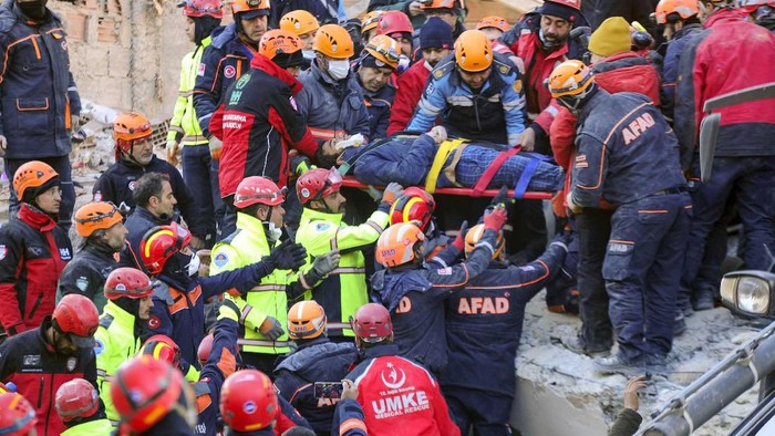 Rescue workers carry a wounded woman after they rescued her from the debris of a collapsed building following a strong earthquake in Elazig in the eastern Turkey, Saturday, Jan. 25, 2020. The earthquake rocked eastern Turkey on Friday, causing some buildings to collapse and killing scores of people, Turkish officials said. (IHA via AP)
