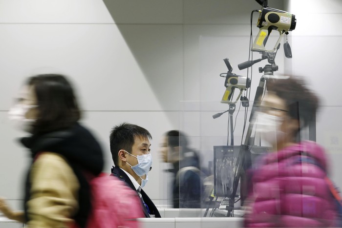 Airport personnel look at thermal scanners as they check on arriving passengers at Manilas international airport, Philippines, Thursday, Jan. 23, 2020. The government is closely monitoring arrival of passengers as a new coronavirus outbreak in Wuhan, China has infected hundreds and caused deaths in that area. (AP Photo/Aaron Favila)