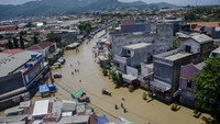 Warga melintas di genangan banjir di Jalan Raya Dayeuhkolot, Kabupaten Bandung, Jawa Barat, Minggu (26/1/2020).