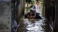 Warga berjalan membawa perabotan melewati genangan di kawasan Andir, Kabupaten Bandung, Jawa Barat, Minggu (26/1/2020).