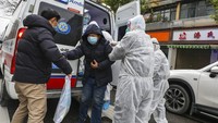 Sejumlah petugas membantu salah seorang pasien keluar dari mobil ambulans di kawasan Wuhan, China, pada Minggu (26/1/2020) lalu. Chinatopix via AP.