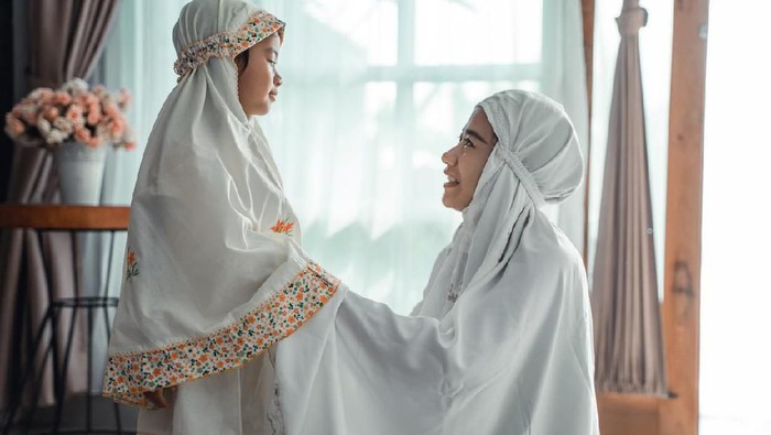 muslim mother help her young daughter to put the scarf on before pray