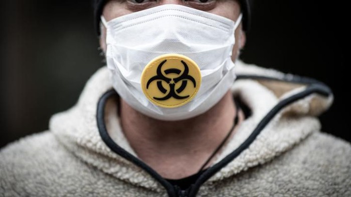 virus corona Man wearing a surgical mask with a biohazard logo close up.