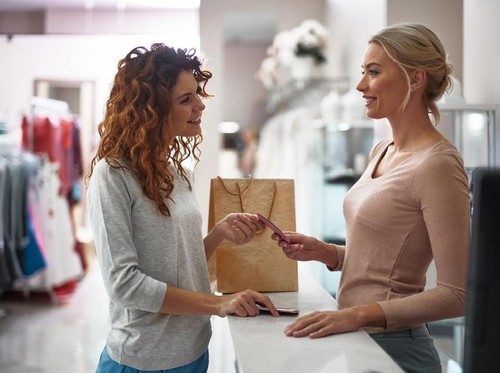 Happy woman in the shop holding a pile of shoes