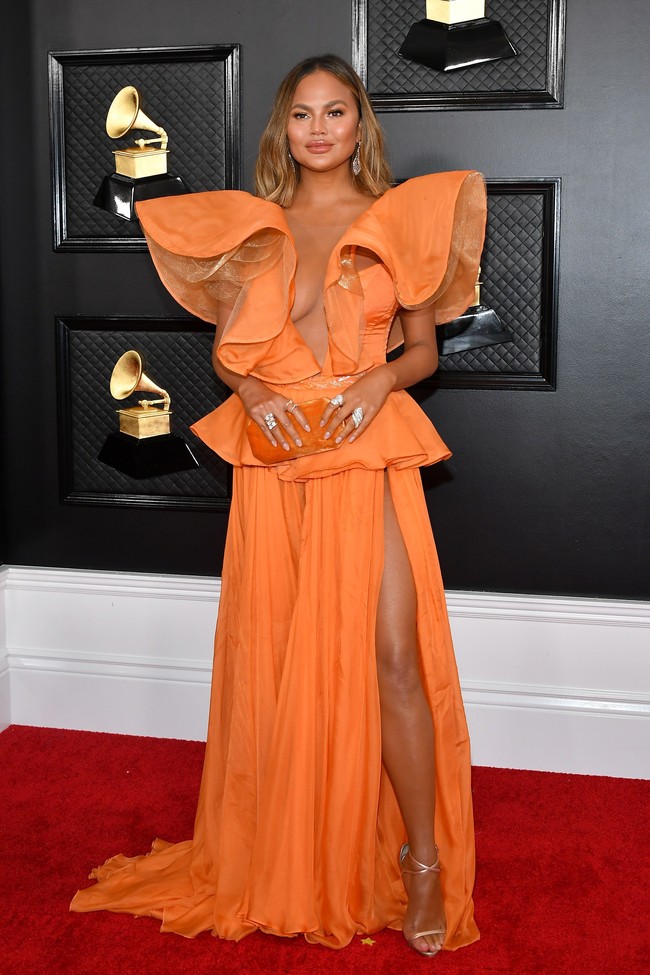 Chrissy Teigen tak suka bermain aman ketika menghadiri ajang sekelas Grammy Awards. Tahun ini, istri John Legend itu memakai gaun oranya Yanina Couture yang hadir dengan belahan tinggi pada rok dan belahan di area dada. (Foto: Amy Sussman/Getty Images)