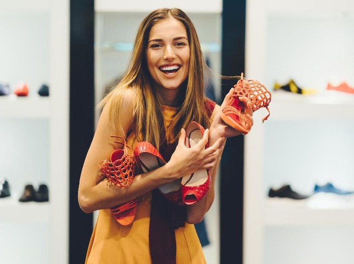 Happy woman in the shop holding a pile of shoes