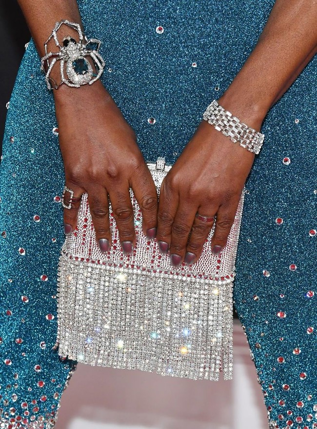 Penampilannya disempurnakan dengan aksesori yang tak kalah bling-bling. Ia menenteng clutch kristal fringe dan gelang laba-laba.  Foto: Getty Images