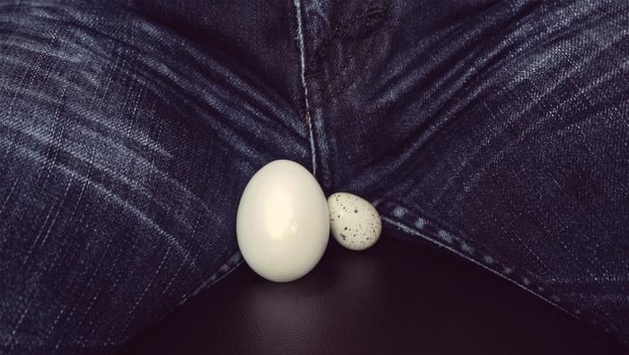 makan sperma two eggs of different sizes between the legs of men. White eggs - a symbol of mans balls