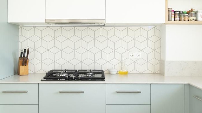 Scandinavian style kitchen with geometric backsplash and blue and white cupboards