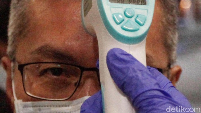 Seorang petugas tengah memeriksa warga yang baru tiba di Bandara Soekarno Hatta, Tangerang, Senin (27/1/2020). Hal tersebut guna mencegah masuknya virus corona yang tengah marak diberitakan.