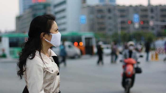 buah kaya vitamin C Beautiful Chinese woman wearing a white face mask against pollution or disease
