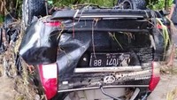Sebuah mobil hanyut dan terbalik di bawah pohon bambu.