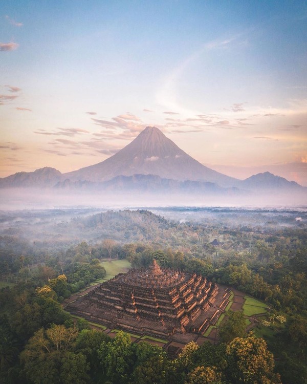 Candi Borobudur tengah jadi perbincangan karena unggahan dari Instagram Kemenparekraf. Postingan tersebut memperlihatkan foto Borobudur dengan latar sebuah gunung yang lancip. (Instagram/indtravel)