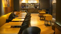 Seorang pengunjung menunggu makanan pesanannya disajikan di salah satu tempat makan yang berada di pusat perbelanjaan Kota Beijing, yang sepi akibat kekhawatiran warga terkait penyebaran virus corona jenis baru yang semakin meluas.
