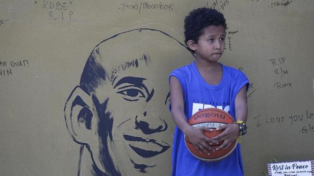 Boys plays beside images of former NBA basketball player Kobe Bryant at the 