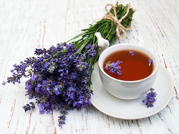 Glass cup of green camomile tea and wild herbs on the rustic wooden background. Herbal organic tea as wellness and relax concept