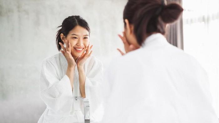 1138747364 Asian woman cleaning face front of mirror, skin care and cosmetic removal concept