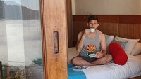 Berpose seolah-olah menyeruput kopi dalam cangkir dengan pemandangan kamar hotel, Mr. Dennis menyebut bahwa sebenarnya cangkir itu tidak ada isinya. Foto: Instagram @gurukumrd