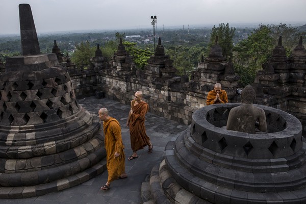 Sesekali pengunjung bisa melihat para biksu berdoa di jajaran patung Buddha di atas candi. (Getty Images)