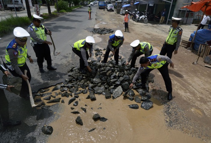 Kapala Satuan lalu lintas Polresta Bandar Lampung Kompol Reza Khomaini (kanan) beserta jajaran menimbun jalan berlubang yang digenangi air di jalan Ryacudu Bandar Lampung, Lampung, Kamis (30/1/2020). Penimbuan jalan tersebut bertujuan untuk mengurangi angka kecalakaan lalu lintas akibat jalan berlubang dan kemacetan. ANTARA FOTO/Ardiansyah/pd.