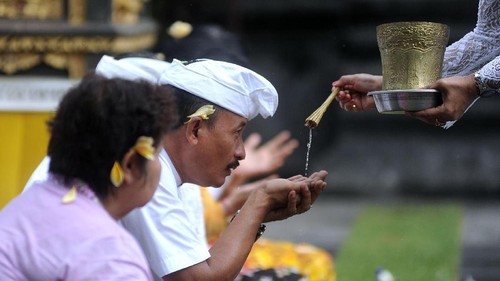 Pemuka agama Hindu memercikkan air suci saat persembahyangan bersama di Pura Luhur Candi Narmada Tanah Kilap, Denpasar, Bali, Jumat (31/1/2020). Persembahyangan yang dilakukan Dinas Pariwisata Provinsi Bali dan diikuti sejumlah pelaku industri pariwisata tersebut diselenggarakan untuk mendoakan keselamatan dunia dan memohon agar Bali dijauhkan dari penyebaran virus Corona. ANTARA FOTO/Fikri Yusuf/nz